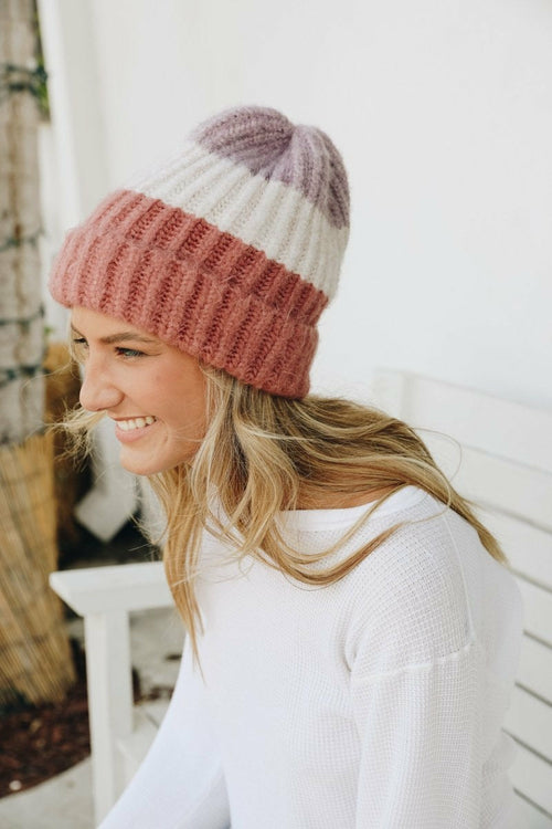 Girl smiling wearing her fashionable colorblock beanie, shown in pink here.